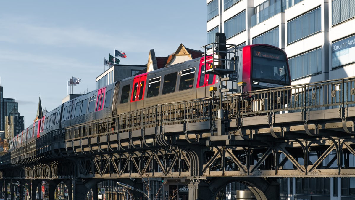 A commuter train on an elevated railway bridge in Hamburg's urban landscape.